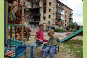 children in a playground in front of bombed buildings in Ukraine