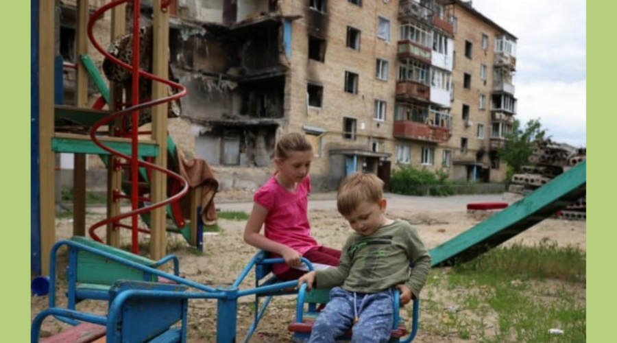children in a playground in front of bombed buildings in Ukraine