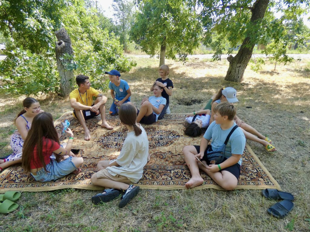 kids camp with rocket holes in school lawn visible in war-torn ukraine