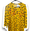 Yellow long-sleeve blouse with black polka dots and orange sunflower prints on a hanger, front view showing collar and button placket.