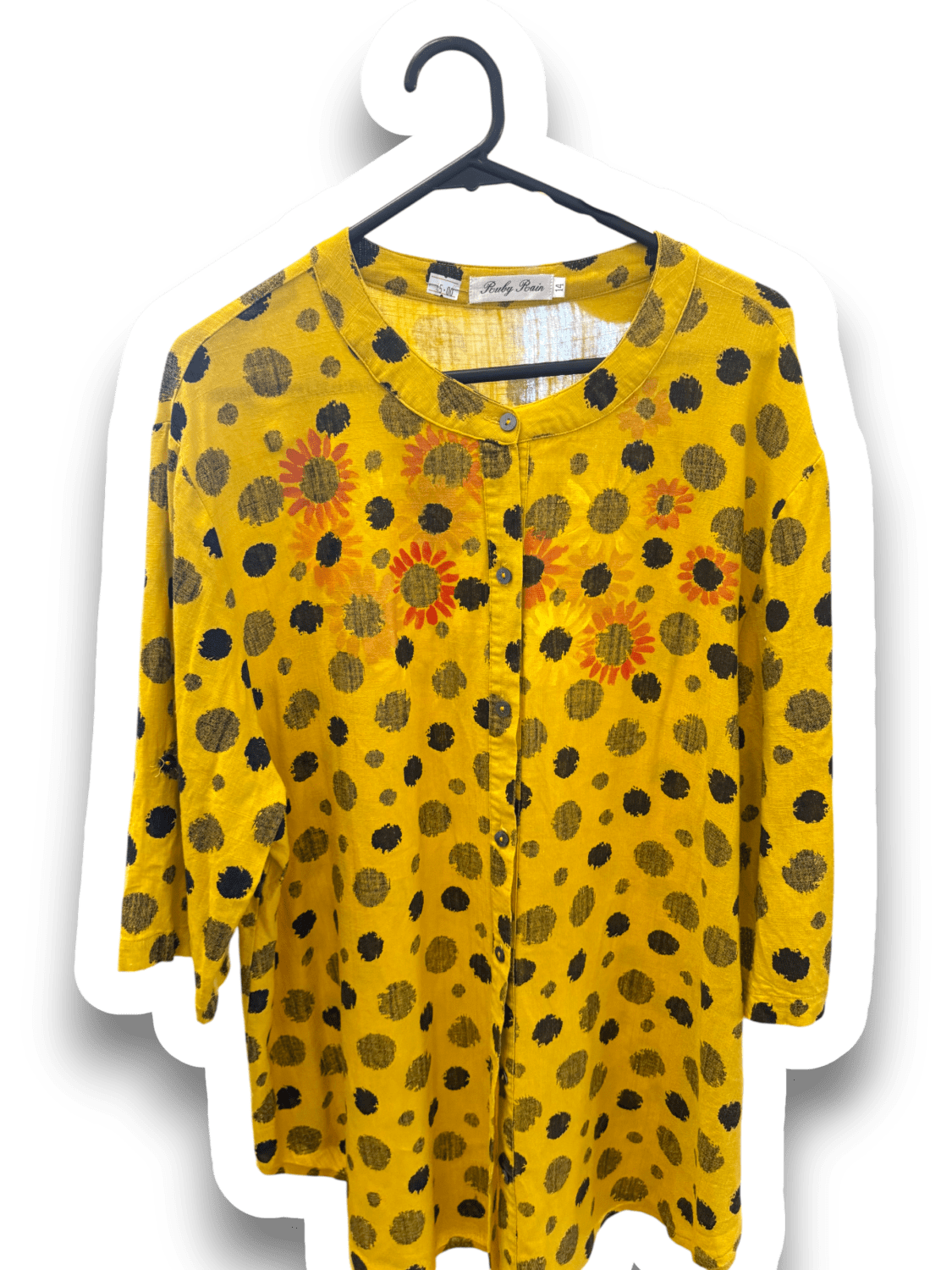 Yellow long-sleeve blouse with black polka dots and orange sunflower prints on a hanger, front view showing collar and button placket.