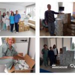 Group of medical staff posing with boxes of medical supplies in a clinic lobby or reception area.