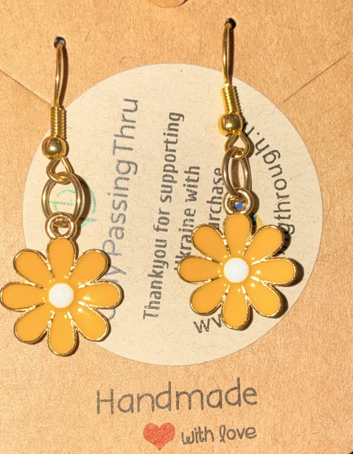sunflowers Handmade gold-tone earrings with yellow daisy charms and white centers, mounted on a beige display card