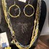 Beaded yellow and blue jewelry set on a black display board, featuring large circular hoop earrings and multiple bead strands with a price tag above.