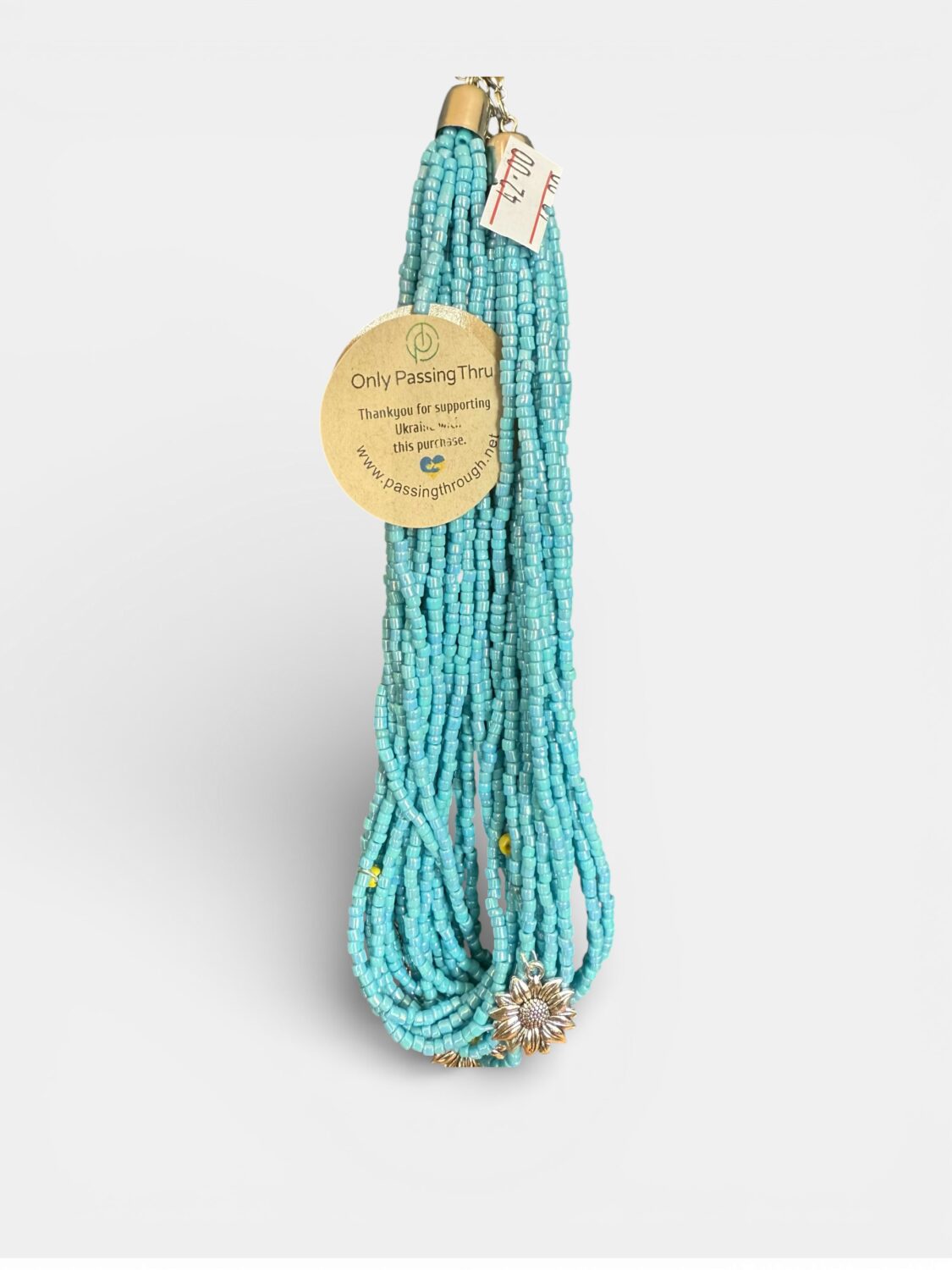 Turquoise multi-strand beaded necklace with a gold-tone sunflower pendant and a round tag reading 'Only Passing Thru'.
