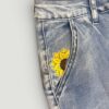 Blue denim jeans with a yellow sunflower embroidery on the front pocket area.