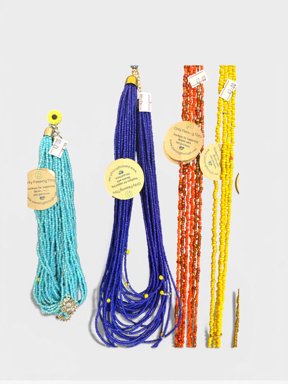 Colorful beaded necklaces in turquoise, royal blue, red, and yellow hanging against a light background with price tags.