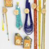 Assorted beaded jewelry: turquoise, cobalt blue, red, orange, and yellow necklaces and bracelets laid out on a white surface, some in packaging.