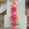 Bracelet with pink gradient rose beads and green leaves on white carding surface.