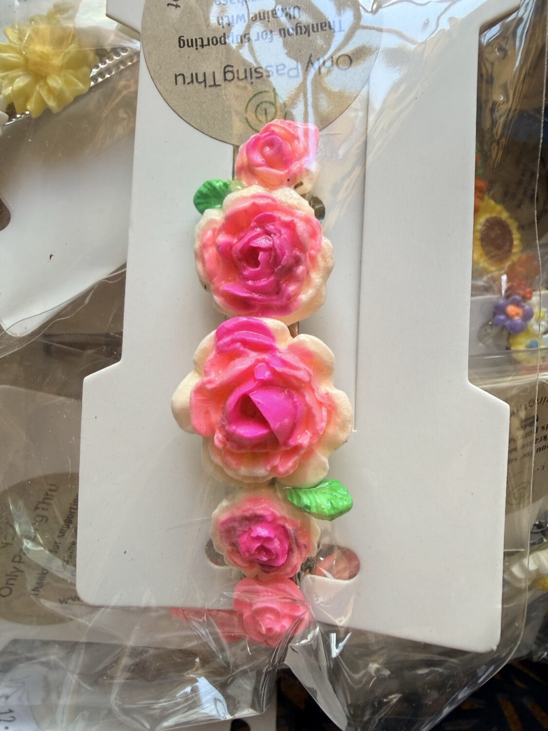 Bracelet with pink gradient rose beads and green leaves on white carding surface.