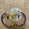 Beaded hoop earrings in cobalt blue and yellow seed beads on a brown display card.