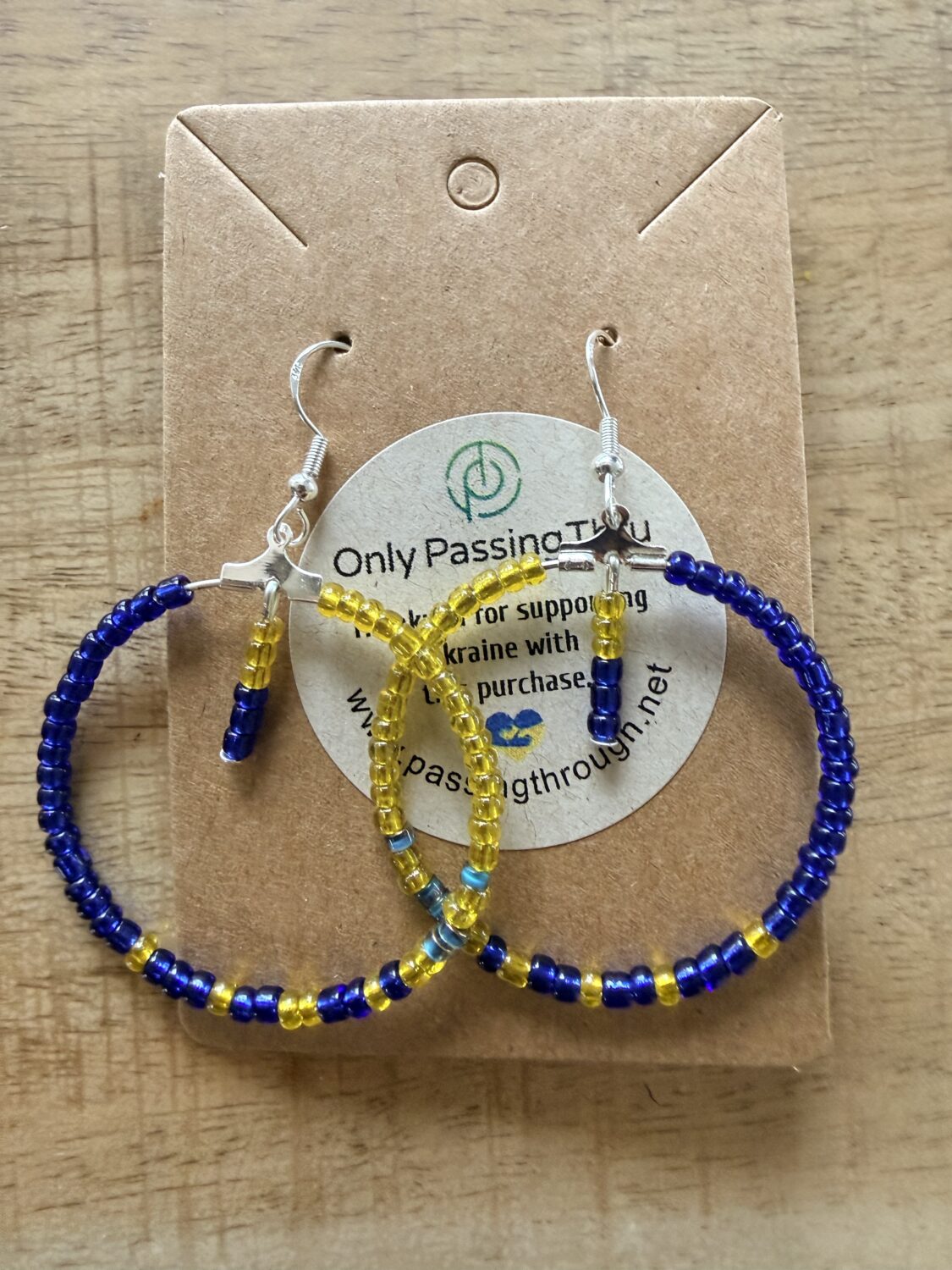 Beaded hoop earrings in cobalt blue and yellow seed beads on a brown display card.