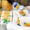 White fabric napkins with bright yellow sunflower prints laid on a couch.