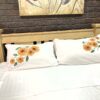 Wooden bed frame against a dark brick wall with white bedding and sunflower-patterned pillows.