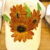 White cap with a large orange sunflower print on the front.