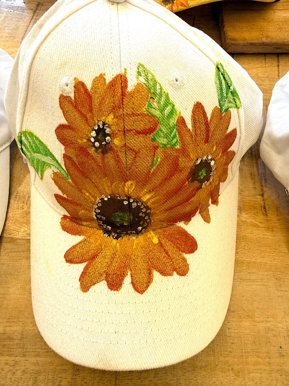 White cap with a large orange sunflower print on the front.