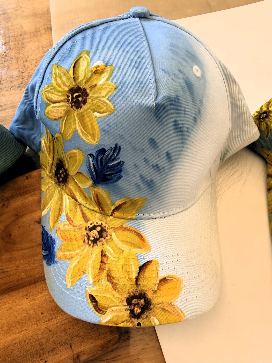 Light blue baseball cap with yellow floral embroidery along the front panel and brim edge.