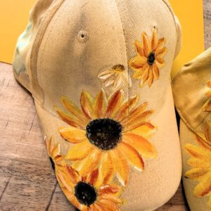 Beige cap decorated with large yellow sunflowers embroidered on the front.