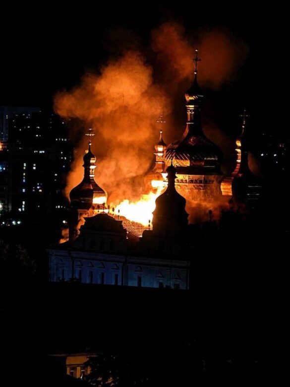 Night scene of a church with onion domes engulfed in orange flames and rising smoke against a dark sky