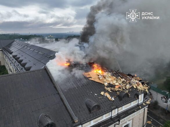 Roof fire on a large building with flames and thick smoke billowing from the damaged area; emergency services watermark in the corner.