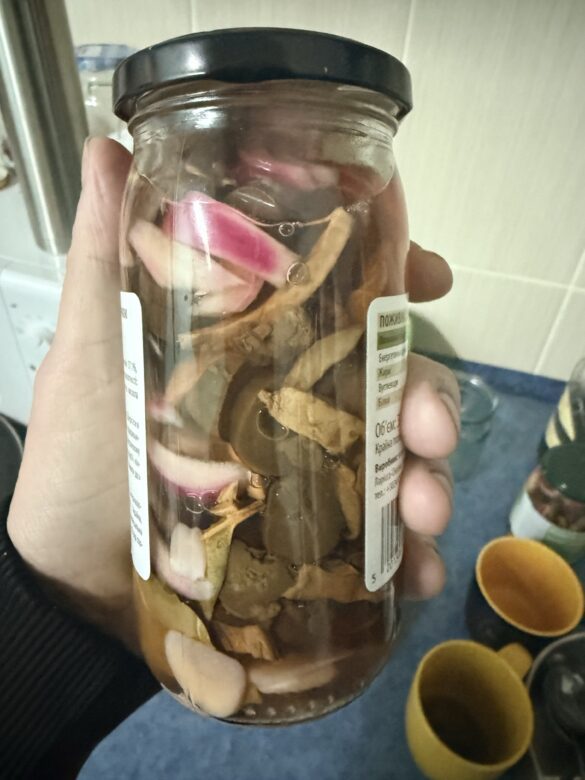 Jar filled with mixed pickled vegetables and root slices soaking in brine.