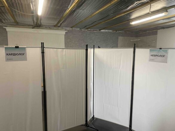 IMG_8713 Temporary medical consultation booths with white curtains; signs read 'Кардиолог' and 'Невролог' in Cyrillic.